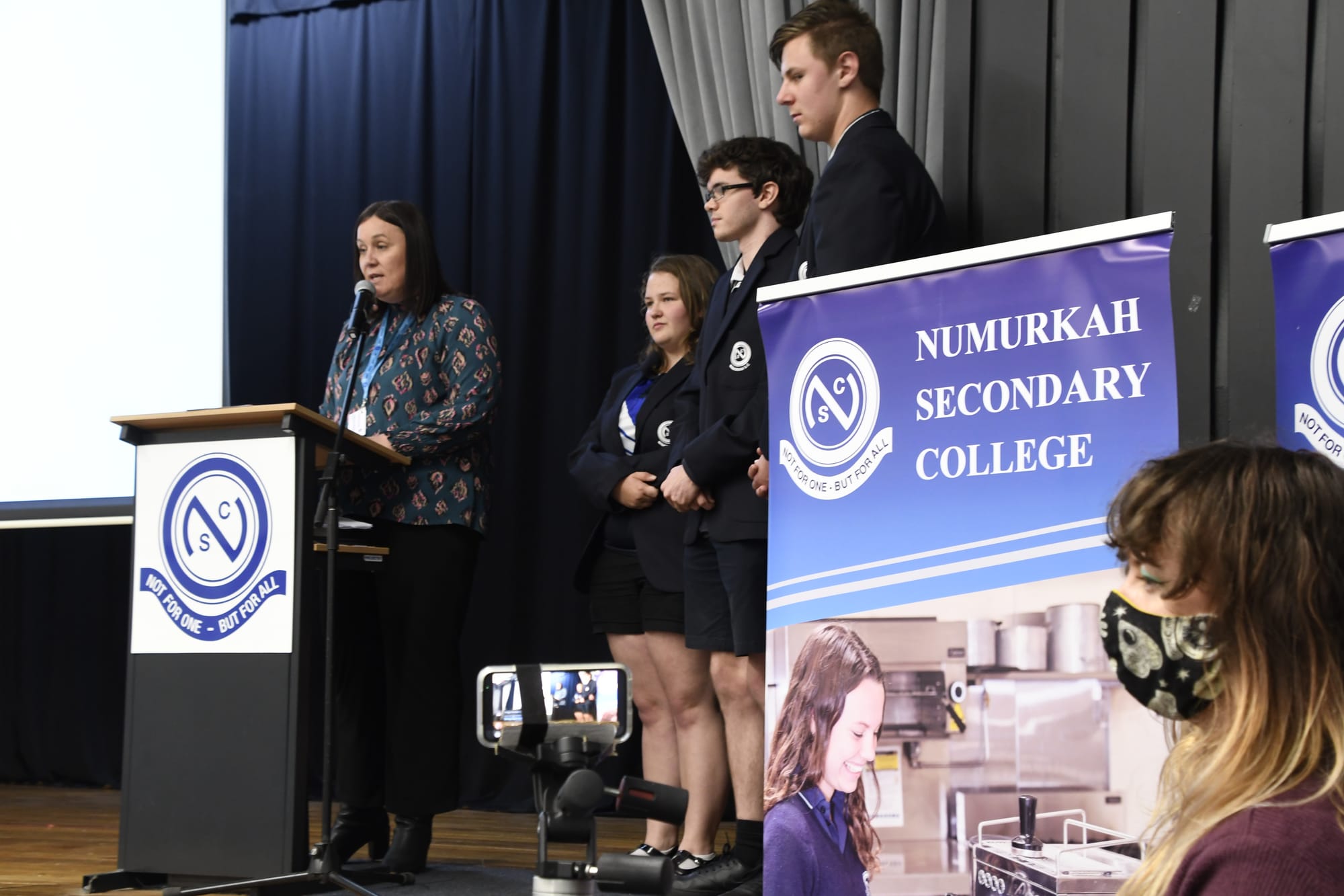 Live stream ... NSC principal Claire Kelly commences the assembly with a moving speech, flanked by 2020 college captains Kaitlyn Dicker, Matthew O’Flynn and Jack Millen, while art teacher Francxs Sadler runs the live stream.