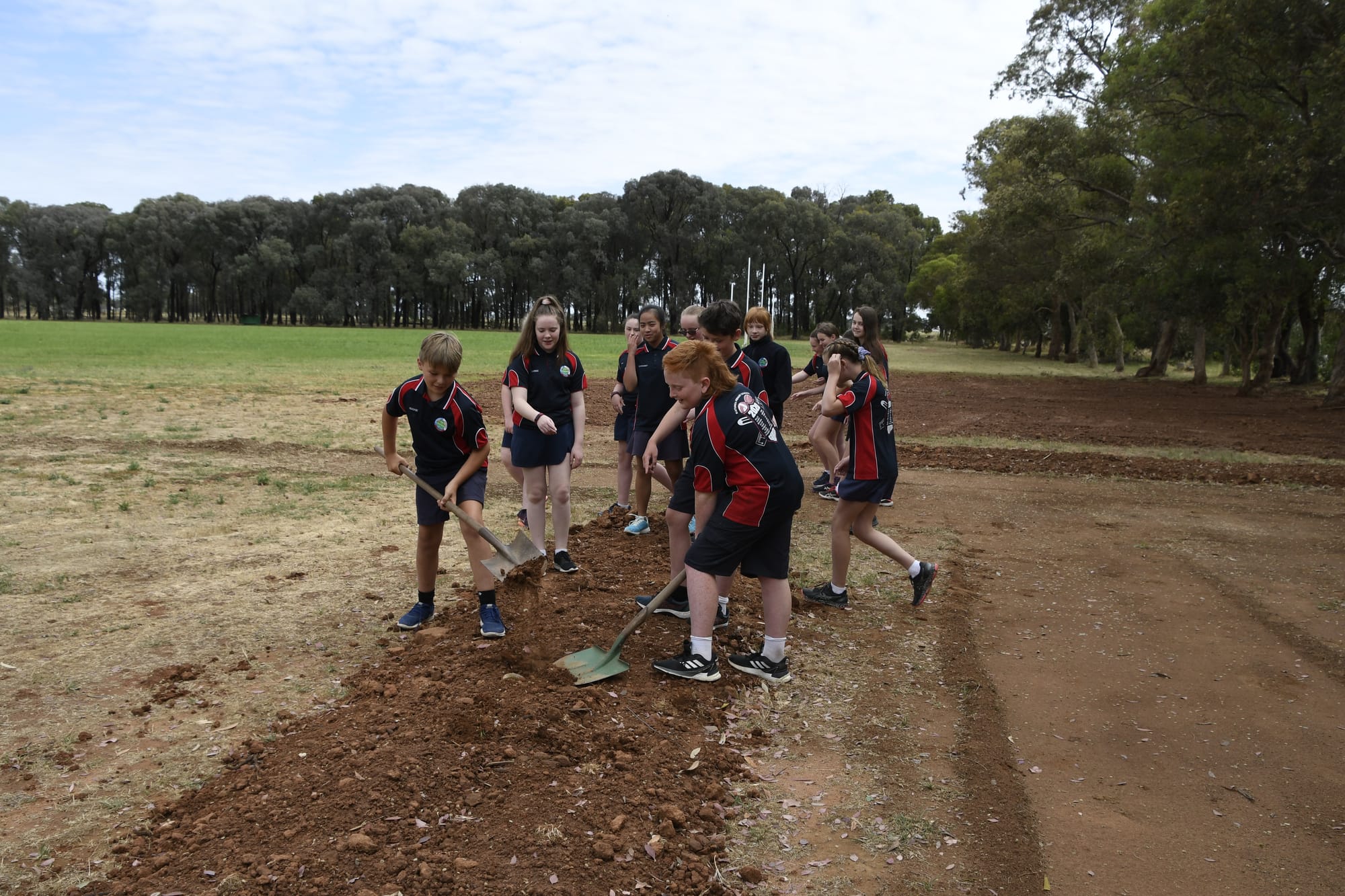 Team effort ... Hughie Stammers, Gabbie Moulder and Harry Ryan working hard to dig out a garden bed, next to the hole. 