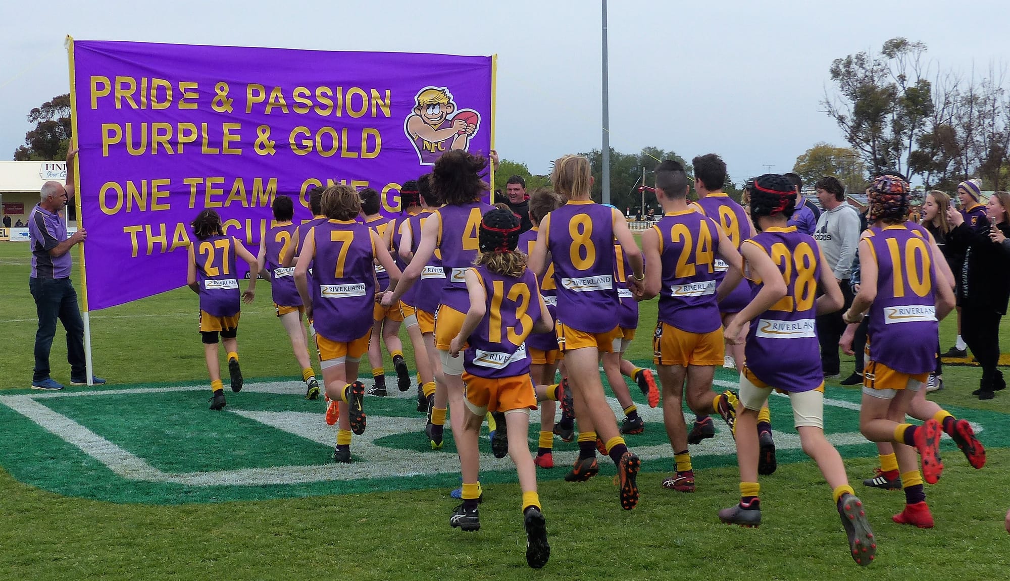 Lets stick together … The U/14s run through the banner prior to the start of play.